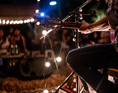 A musician wearing a plaid shirt is playing guitar on stage.Concert,mini concert and music festivals.